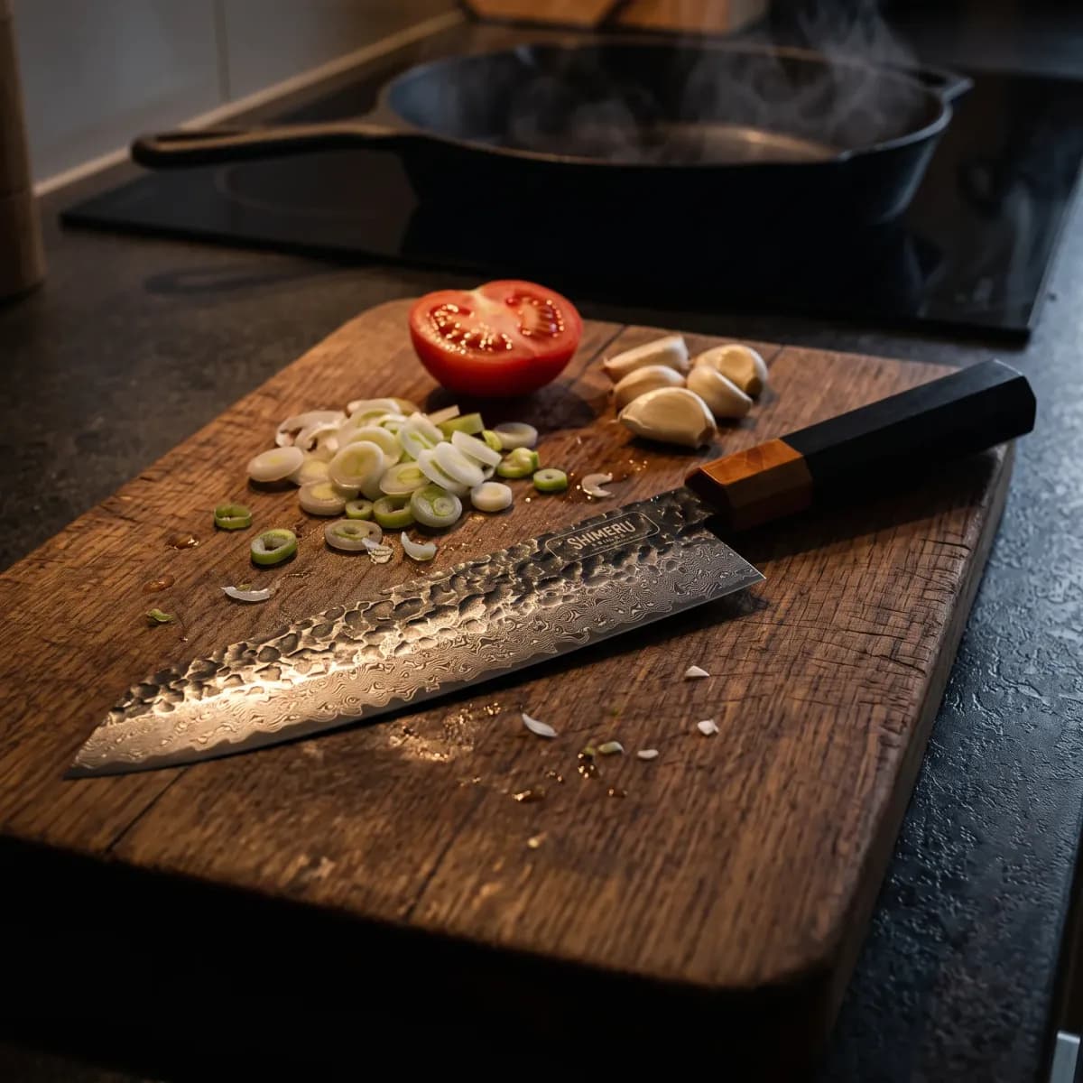Kurobe 9.5" Damascus Steel Kiritsuke Knife on an oak board with spring onions, tomato and garlic