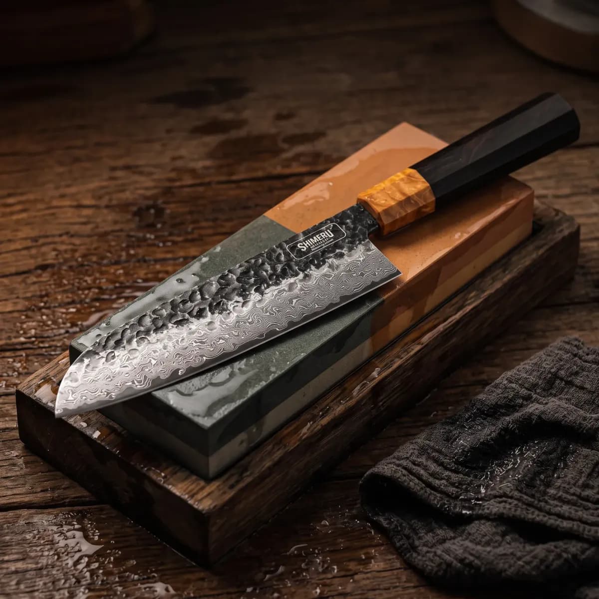 Dark Grain 7" Damascus Steel Santoku Knife being sharpened on a wet whetstone